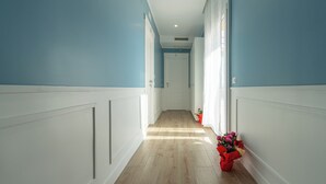 Un pasillo con suelo de madera clara, paneles blancos y paredes azules.