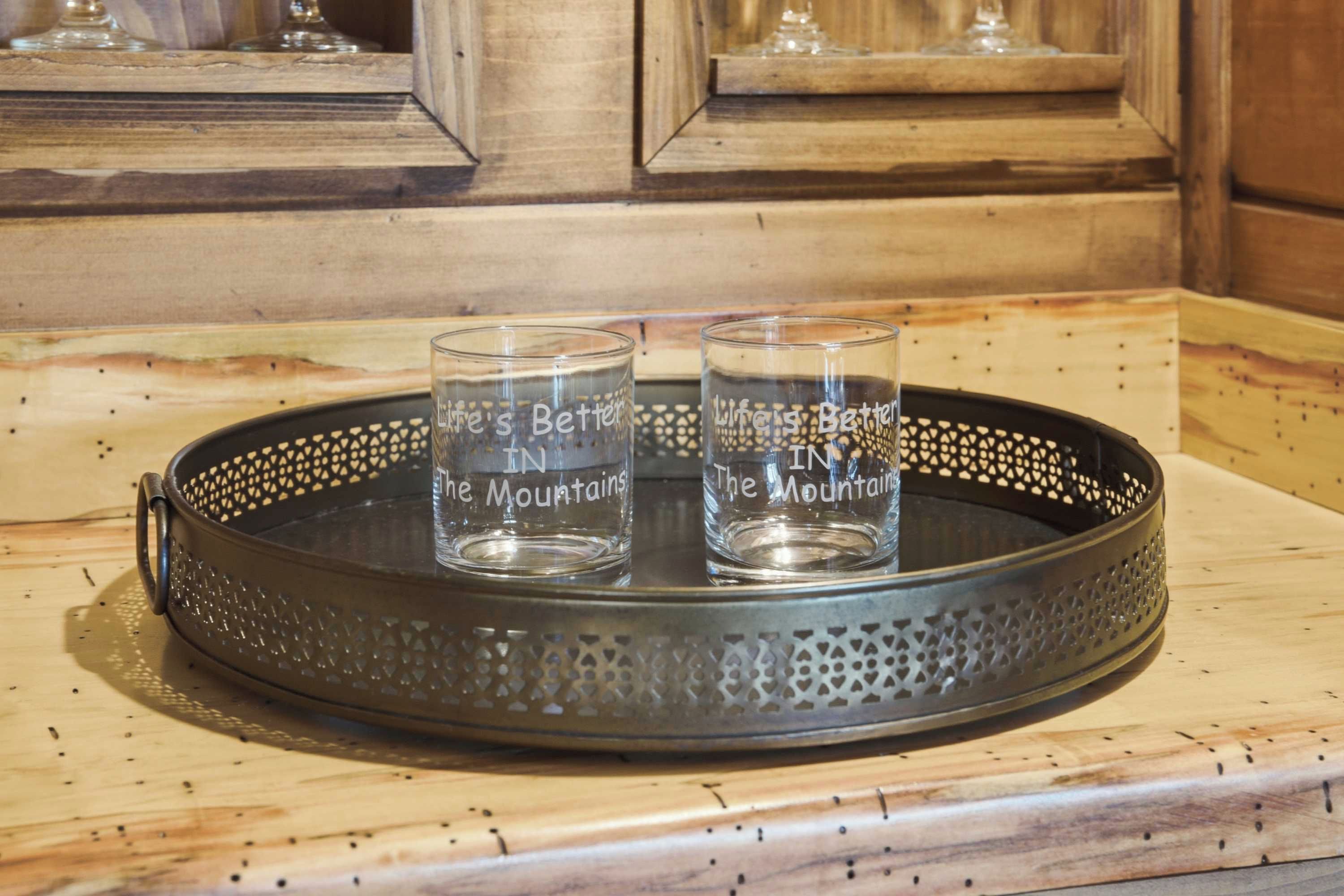 Due bicchieri trasparenti con l'iscrizione 'Life is Better in the Mountains' su un vassoio metallico.
