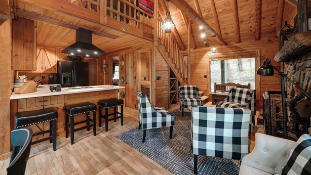 Interior de una cabaña de madera con cocina, comedor y zona de estar.