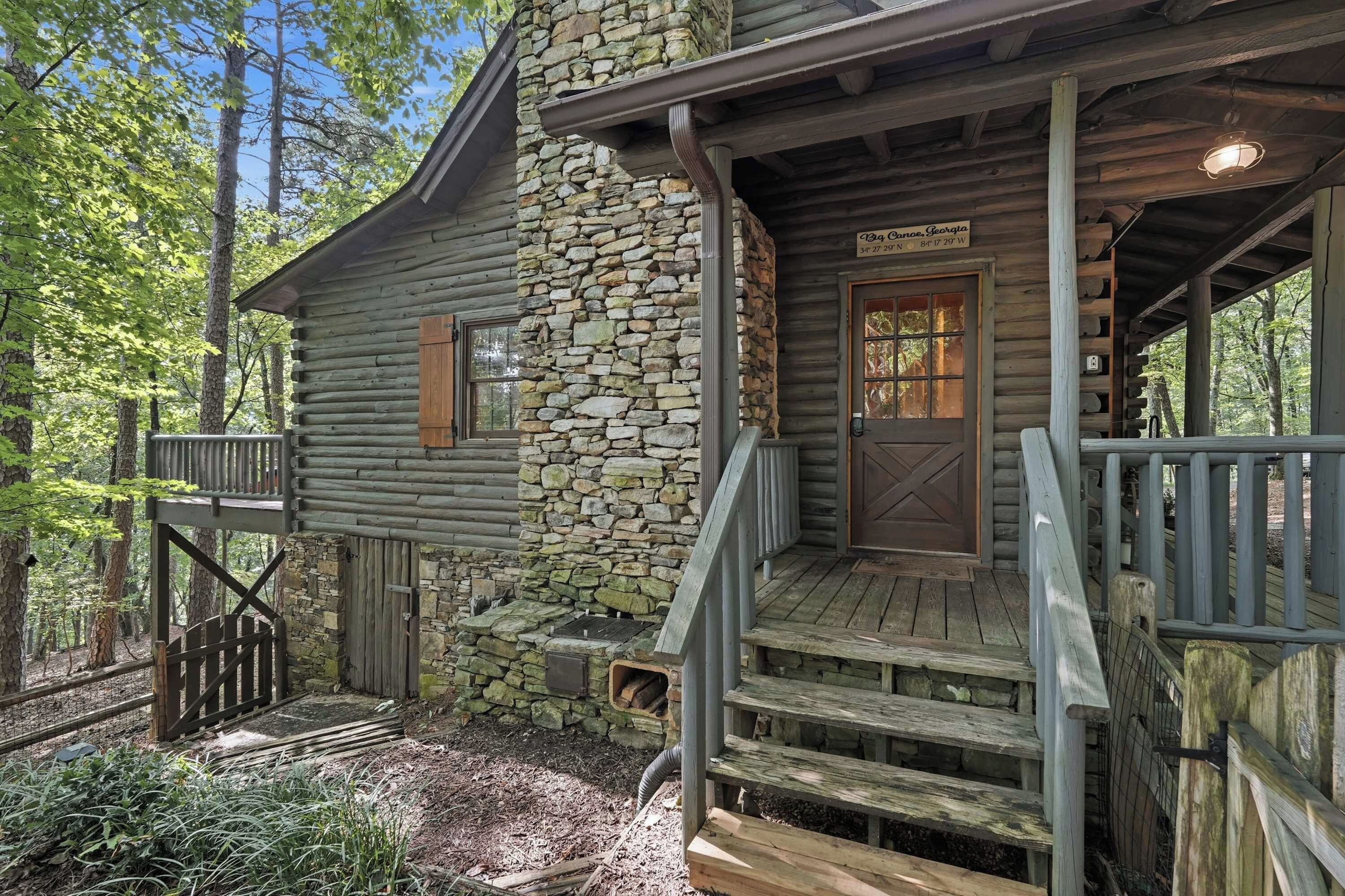 A rustic cabin with a stone wall, wooden steps, and a porch.