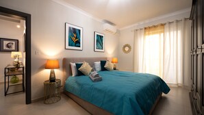 Een slaapkamer met een bed, twee bedlampjes, een wandairconditioner en een raam met gordijnen.