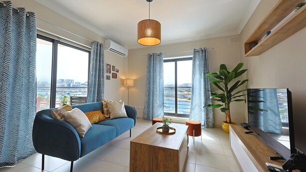 Een moderne woonkamer met een blauwe bank, een houten salontafel en een televisie.