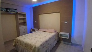 Ein Schlafzimmer mit einem Bett, Nachttischen, einem Kleiderschrank und einem Deckenventilator.