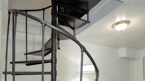 Una escalera de caracol con estructura metálica negra que conduce a un nivel superior.