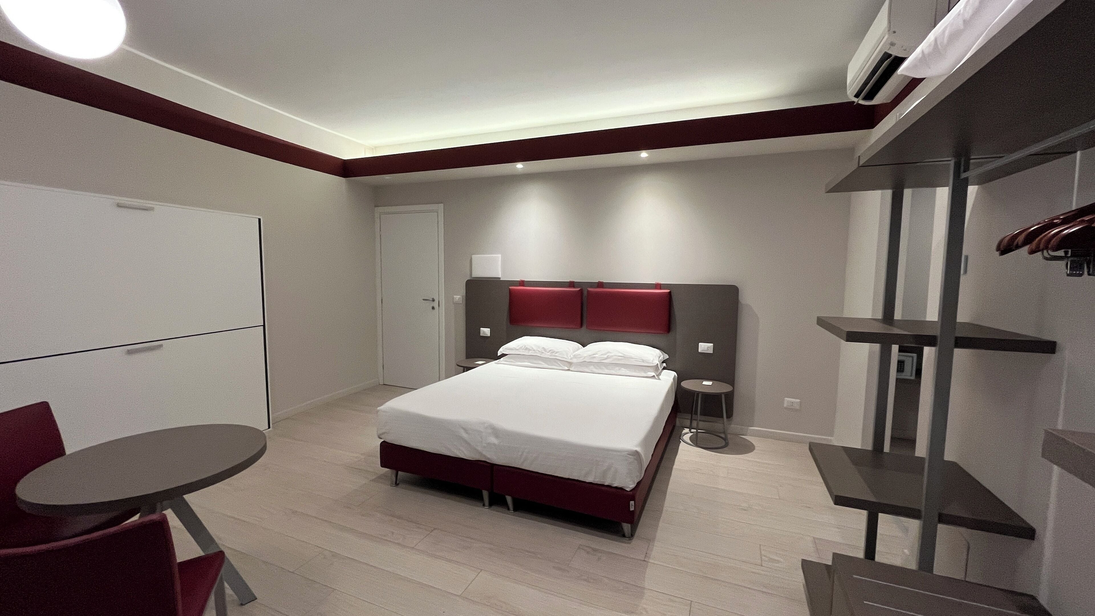 A modern hotel room with a bed, bedside tables, a desk, and a chair.