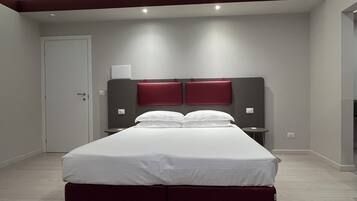 Una habitación de hotel moderna con una cama grande, una mesita de noche y una lámpara de pared.