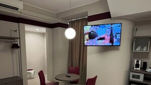 A modern living room with a flat-screen TV mounted on the wall, a round dining table with two chairs, a sofa, and a coffee table. - Guest House Borgo Yporegia (Ivrea)