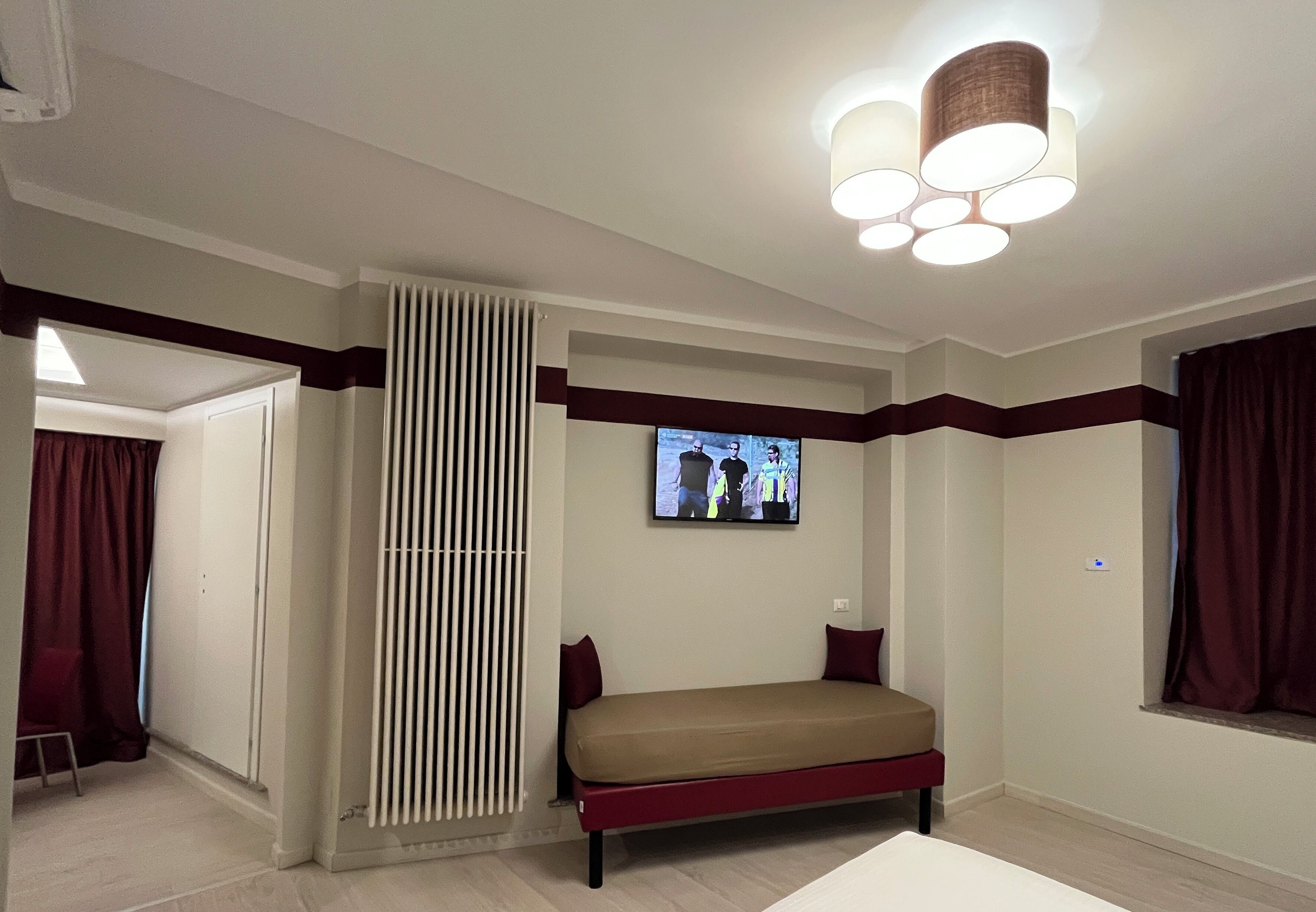 Une chambre à coucher moderne avec un lit, un téléviseur fixé au mur et un luminaire au plafond.