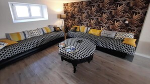 Sala de estar com sofá, mesa de centro e papel de parede estampado.