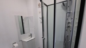 Um banheiro moderno com chuveiro em gabinete de vidro, vaso sanitário e pia.