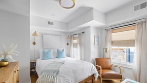 A bedroom with a large bed, a wooden dresser, a chair, and a window with curtains. - A newly renovated classic Charleston home in the heart of downtown  (Charleston)