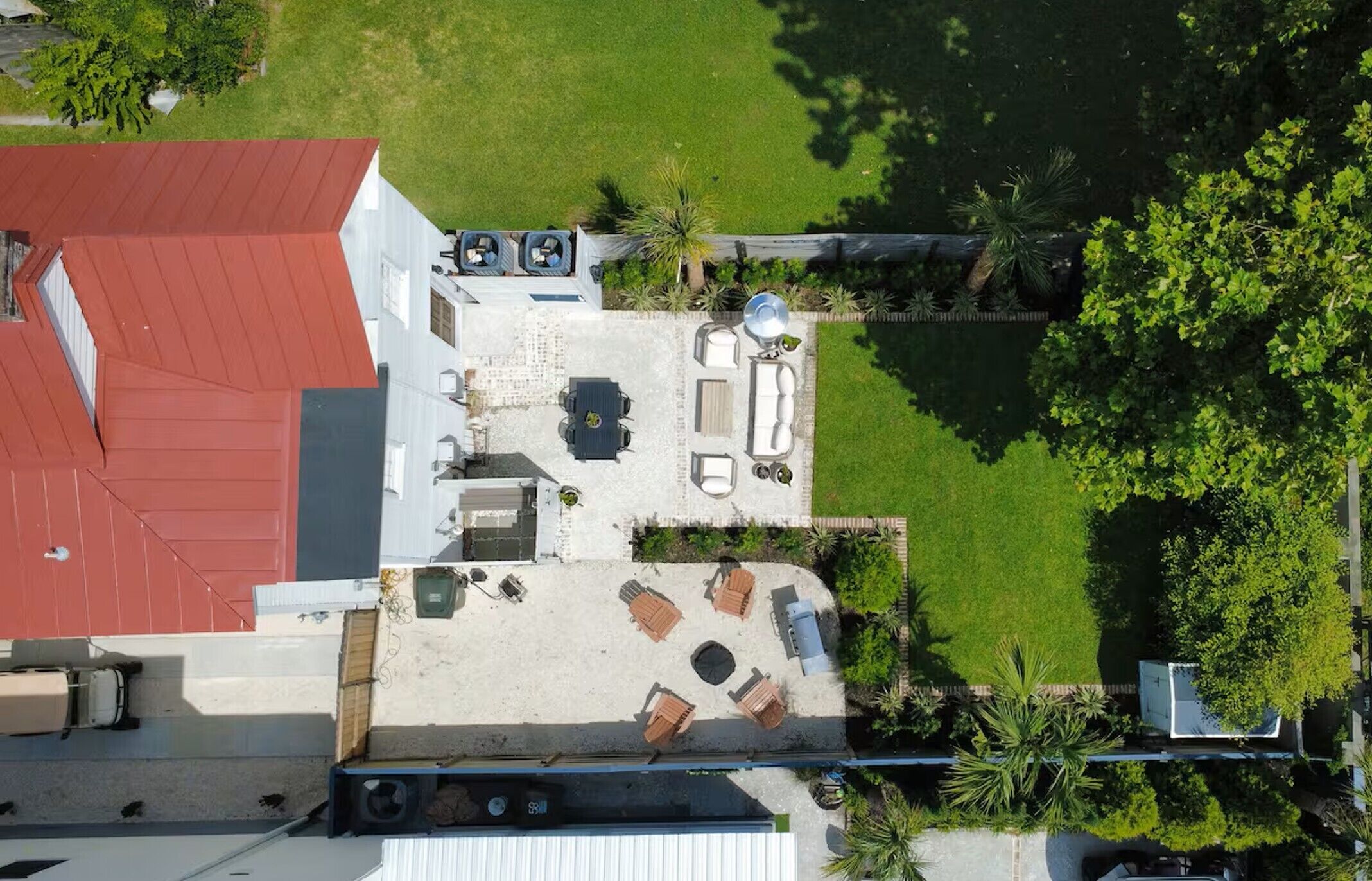 An aerial view of a rooftop patio with outdoor furniture, a pool, and surrounding greenery.