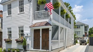 A two-story house with a balcony, a front door, and a small porch. - A newly renovated classic Charleston home in the heart of downtown  (Charleston)