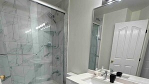 Un bagno moderno con doccia vetrata, un water bianco e un lavabo con specchio.