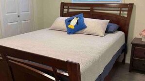 Una camera da letto con un letto di legno, una finestra con persiane, una porta e un comodino.