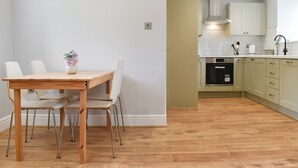 A modern kitchen with wooden flooring, a dining table with chairs, and light-colored cabinets. - UK47385 - The Deer Den (Easington, near Staithes)