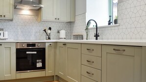 A kitchen with light-colored cabinets, a stainless steel range hood, a dishwasher, and a coffee maker. - UK47385 - The Deer Den (Easington, near Staithes)