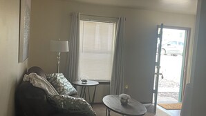 A living room with a sofa, a small round table, a lamp, and a window with blinds. - Beautiful little Magnolia in Las Cruses  (Las Cruces)