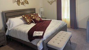 A neatly made bed with a white comforter and a maroon throw blanket, a wooden headboard, a bedside table with a lamp, and a bench at the foot of the bed. - Beautiful little Magnolia in Las Cruses  (Las Cruces)