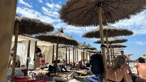 En strand med flere parasoller af strå, der giver skygge.