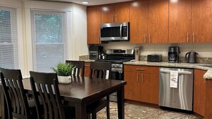 A modern kitchen with wooden cabinets, stainless steel appliances, and a marble floor.