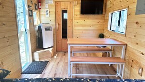 A compact wooden cabin with a kitchenette, a small table, and a bed with a star-patterned rug.