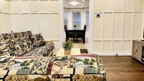 A bedroom with a large bed, a sofa, and a dining area with a table and chairs.