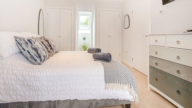 A bedroom with a bed, a dresser, and a TV mounted on the wall. - 2 bedroom accommodation in Lamlash (Lamlash)
