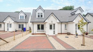 A row of modern, single-story houses with a uniform design, featuring a central entrance and a paved driveway. - 2 bedroom accommodation in Lamlash (Lamlash)