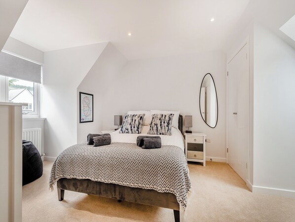 A bedroom with a bed, bedside tables, a mirror, and a window.