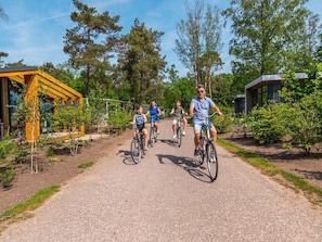 A pathway with people riding bicycles, surrounded by greenery and modern buildings. - Luxury Villa in Arnhem With Parking (Arnhem)