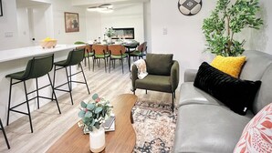 Una sala de estar moderna con un sofá gris, una mesa de centro y un comedor con sillas y una mesa.