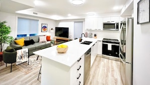 Una cocina moderna con armarios blancos, una isla central y electrodomésticos de acero inoxidable.