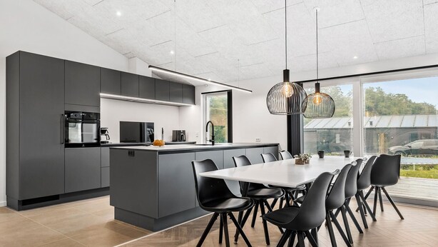 Una cocina moderna con una isla central, sillas negras y una mesa de comedor grande.