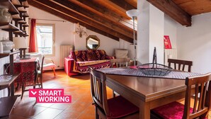 A cozy room with a wooden ceiling, a dining table with chairs, a sofa, and a small table with a lamp. - Comfort Urbano a Porta Maggiore by Wonderful Italy (Bologna)