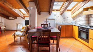 A cozy kitchen with wooden beams, a dining area with a table and chairs, and a view through skylights. - Comfort Urbano a Porta Maggiore by Wonderful Italy (Bologna)