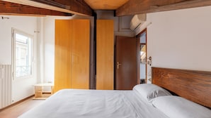 A bedroom with a wooden headboard, a bed with white linens, a wooden wardrobe, and a small bedside table. - Comfort Urbano a Porta Maggiore by Wonderful Italy (Bologna)