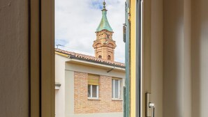 A window with a view of a building with a green roof and a tower with a cross on top. - Comfort Urbano a Porta Maggiore by Wonderful Italy (Bologna)