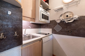 Una cocina compacta con lavavajillas, microondas y pileta.