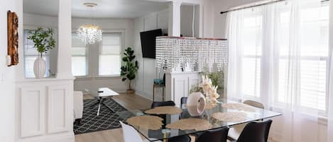 A modern dining area with a glass table, black chairs, and a decorative chandelier.