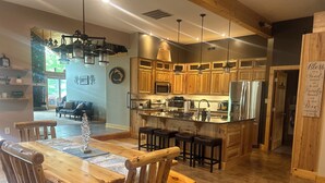 Una cocina amplia con armarios de madera, una isla central con taburetes y un comedor con mesa y sillas de madera.