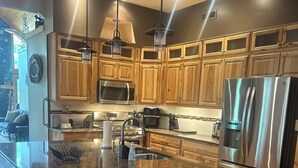 Una cocina moderna con armarios de madera, electrodomésticos de acero inoxidable y una isla central con taburetes.