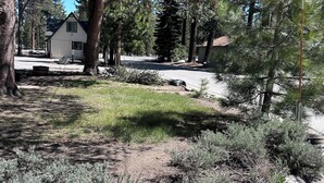 Un quartiere residenziale con una casa a due piani, un vialetto e alberi circostanti.