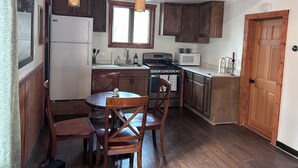 Una cucina con mobili in legno, un frigorifero, un fornello, un forno a microonde e un'area pranzo con tavolo e sedie.