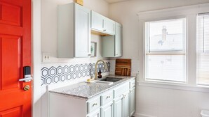 A kitchen with white cabinets, a red door, and a window with blinds. - Niagara RiversideView Balcony GameRoom WiFi Free Parking King bed Crib sleep 9 (Buffalo)