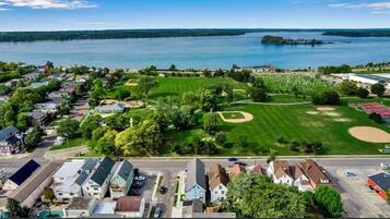 A residential area with houses, a park with a baseball field, and a large body of water in the background.