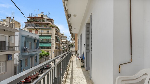 A narrow balcony with a metal railing, a white chair, and a view of adjacent buildings. - Apartment 'Family, Enjoy Athens, Apt 90 Cm' with Private Garden, Wi-Fi and Air Conditioning (Athina)