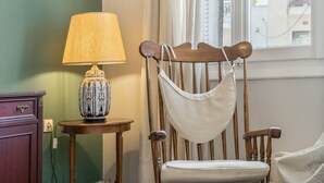 A wooden chair with a white cushion, a lamp on a small table, and a green wall. - Apartment 'Family, Enjoy Athens, Apt 90 Cm' with Private Garden, Wi-Fi and Air Conditioning (Athina)