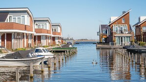 A canal lined with modern houses, boats docked along the water, and a clear blue sky. - Waterside Escape With Easy Access (Uitgeest)