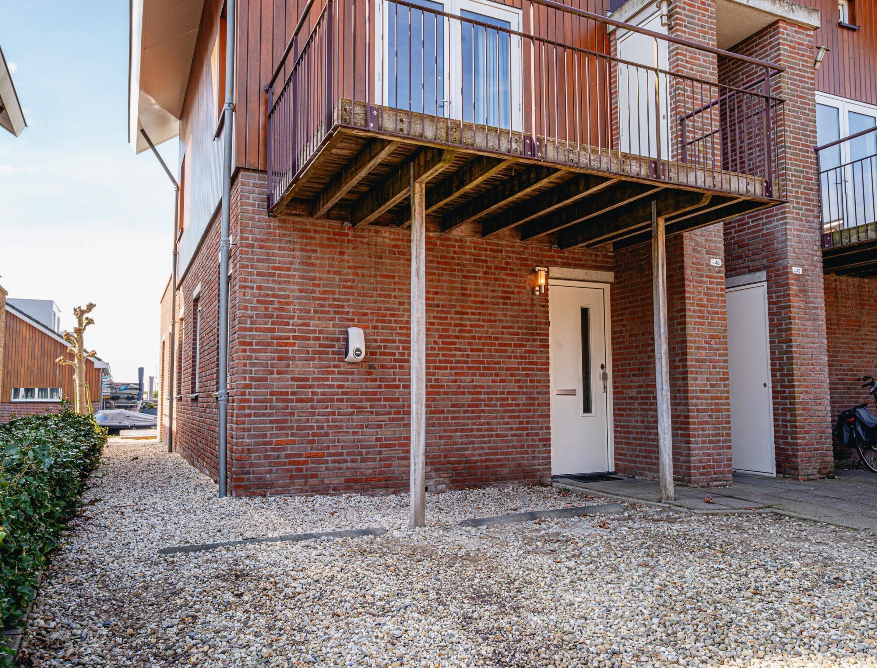 Un immeuble avec une façade en briques, une porte blanche et un balcon doté de rampes en métal.
